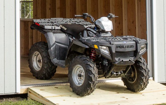 Four-wheeler at the door of a Light Grey High Barn Carriage Shed built by Adirondack Storage Barns