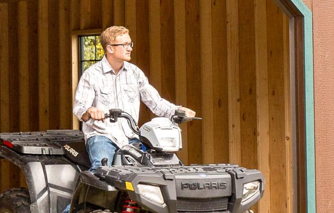 Man on four-wheeler using a Cottage Carriage Shed built by Adirondack Storage Barns