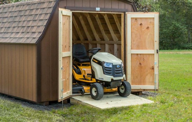 Brown Mini Barn with a tractor driving out the door by Adirondack Storage Barns