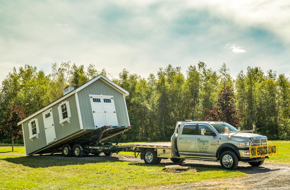 Delivery truck sliding new shed off of trailer